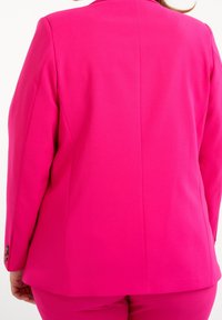 Blazer rosa brillante con un diseño estructurado, que presenta una textura suave, una abertura trasera simple y detalles de botones en las mangas.