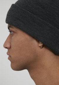 Gray knit beanie with a ribbed texture, snug fit, featuring a small, gold hoop earring visible from the side profile.