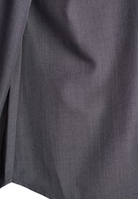 Tuvumā tumši pelēka auduma ar redzamu aušanas tekstūru un smalkiem krokām, rādot šuvēju malu.