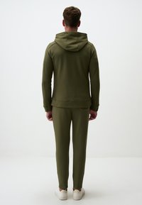 Set di jogger verde oliva composto da una felpa con cappuccio e pantaloni a gamba stretta. Realizzato in tessuto morbido con polsini a costine e una vestibilità comoda.