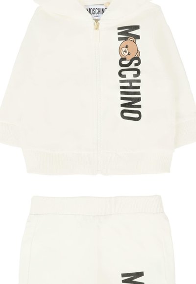Set di tuta bianca per neonato composto da una felpa con zip e pantaloni coordinati. Caratterizzato da testo nero "Moschino" e da una grafica di un orsetto cartone. Texture morbida.