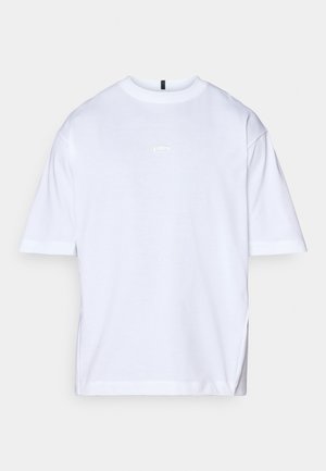 Valge puuvillane T-särk, millel on lõdva istuvusega, lühikesed varrukad, ümmargune kaelus ja väike logo detail rinna peal. Sile tekstuur ja lihtne disain.