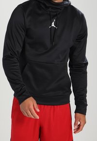 Sudadera con capucha negra de textura suave, con un logo Jumpman blanco en el pecho y un bolsillo canguro en la parte frontal.