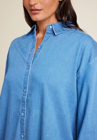 Lys blå, knapp-up skjorte i myk denimstoff med brettet krage, som har en avslappet passform og subtil tekstur.
