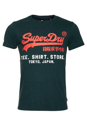 Donkergroen T-shirt met korte mouwen met rode en witte tekst met de woorden "SuperDry," Japanse tekens, en "TEE. SHIRT. STORE. TOKYO, JAPAN."
