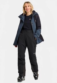 Blue and black ski jacket with a zippered front, paired with black pants. The outfit features waterproof materials and reflective accents.