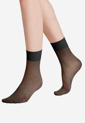 Durchsichtige schwarze Knöchelsocken mit einem festen schwarzen gerippten Bund am oberen Ende. Das Material ist transparent, sodass die Haut durchscheint.