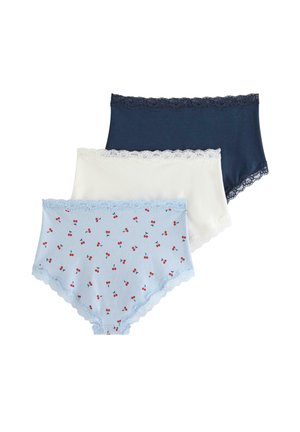 Femme debout devant un fond uni, portant un soutien-gorge bleu foncé assorti et une culotte taille haute avec bordure en dentelle, face à l'objectif.