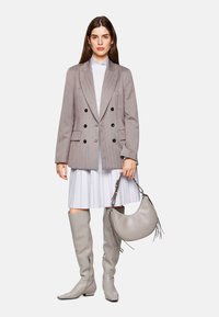Gray double-breasted blazer with black buttons, paired with a white pleated dress, and gray knee-high boots. Holding a gray crescent bag.