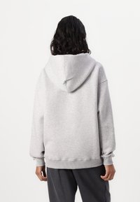 Felpa grigia con cappuccio, caratterizzata da una vestibilità comoda, polsini e orlo a costine. Tessuto liscio con dettagli minimi, che enfatizza la semplicità.