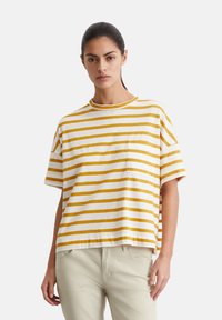 Gestreept T-shirt met korte mouwen in wit en mosterdgeel katoen, met een ronde hals en een linkerkleppen zak. Ontspannen pasvorm.