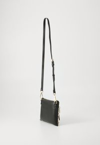 Black leather crossbody bag with gold hardware, rectangular shape, adjustable strap, and smooth texture. Features a zipped closure.