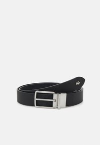 Sorte læderbælte med en sølvfarvet metalspænde. Har et Lacoste-logo på spidsen og en glat overflade hele vejen igennem remmen.