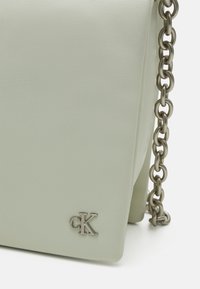 Borsa a tracolla in morbida pelle verde, con un design elegante e un logo "CK" in argento sul fronte.