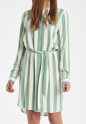Abito a righe verde e bianco, realizzato in tessuto leggero. Presenta un colletto, maniche lunghe e una cintura annodata in vita.