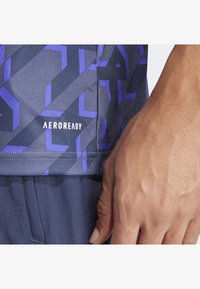 Sportovní tričko AeroReady s geometrickým vzorem v tmavě modré a fialové barvě, s hladkým materiálem a viditelným logem na lemu.