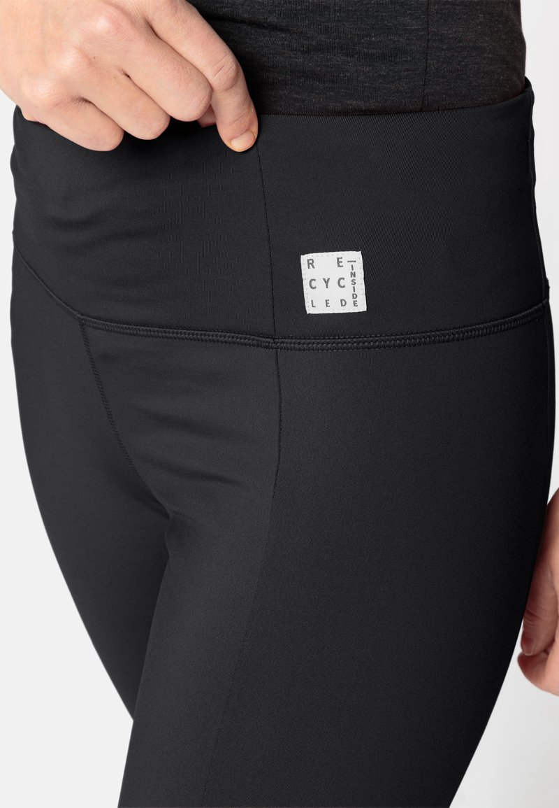 Schwarze Leggings aus recyceltem Material, mit einem breiten Taillenbund und einem strukturierten Logopatch, der mit "RECYCLED INSIDE" beschriftet ist.