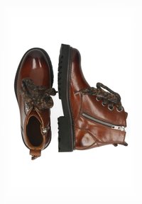 Stivali ankle in pelle marrone con suola in gomma nera spessa. Presentano lacci decorativi e dettaglio con zip sul lato. Design classico con punta rotonda.