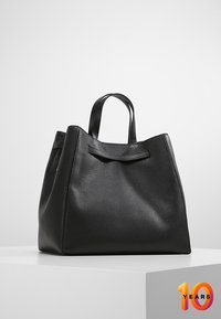 Sort læder tote bag med en tekstureret overflade, der har solide løkker som håndtag og et minimalistisk design. Firkantet form med en flad bund.