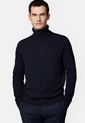 Granatowy sweter z golfem o ryżowej strukturze i mankietach, z małym logo na lewej piersi. Wykonany z miękkiego, dzianinowego materiału.