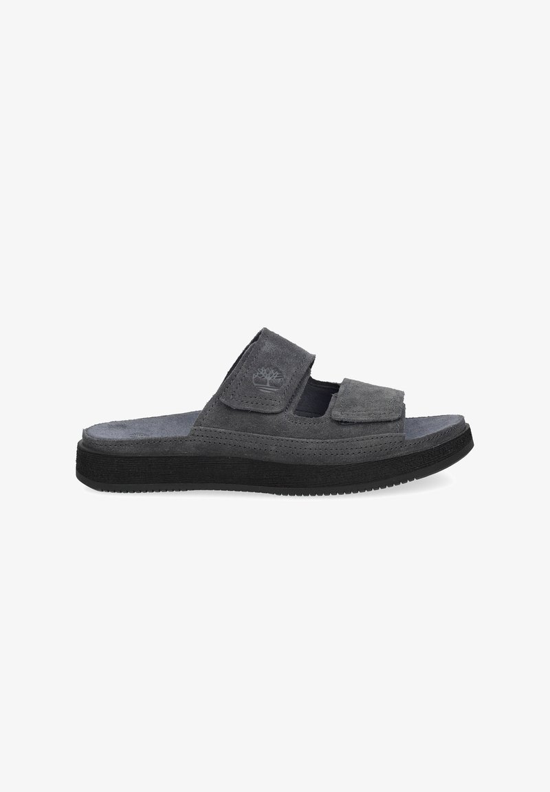Sandale mule en daim gris avec deux sangles ajustables et semelle en caoutchouc noire, avec logo embossé sur la sangle supérieure.