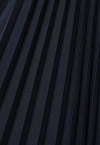 Tissu bleu foncé avec de fines plis verticaux espacés uniformément, créant un motif texturé d'ombres et de reflets.