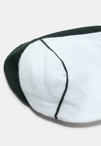 Calze no-show abbinate, una bianca con bordi neri e una verde scuro uniforme, impilate su uno sfondo bianco.