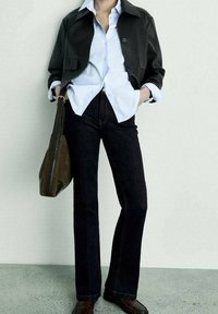 Chaqueta negra, camisa de botones azul clara, jeans acampanados de mezclilla oscura, zapatos marrones y bolso verde oliva. Líneas simples y limpias con colores contrastantes.