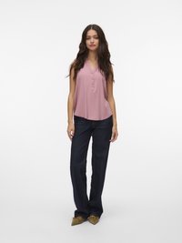 Ärm-lös rosa blus med v-ringning och framknappar, parat med mörkblå vida jeans och olivgröna spetsiga skor.