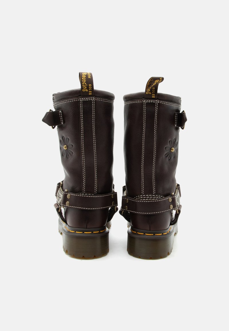 Paar dunkelbrauner Lederstiefel mit gelber Naht, floraler Prägung und Zuglaschen, von hinten auf weißem Hintergrund betrachtet.