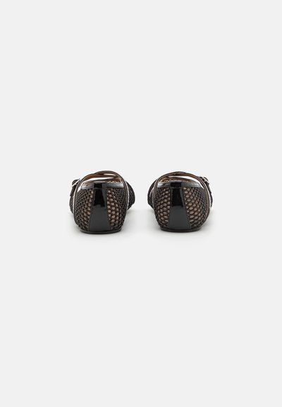 Flats de malla negra con un patrón trenzado, acentos en negro brillante, parte trasera cerrada y un tacón bajo. La textura parece transpirable y suave.