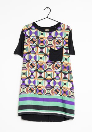 Koszula z krótkim rękawem z czarnymi rękawami, wielokolorowym geometrycznym wzorem z przodu, czarną kieszenią na piersi i poziomymi paskami u dołu, wisząca na wieszaku.