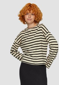 Langärmliges gestreiftes Oberteil in Creme und Schwarz. Es hat einen runden Ausschnitt und eine lockere Passform, mit kontrastierenden Saumnähten.