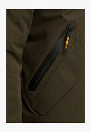 Tejido de chaqueta verde oscuro con una textura suave, que cuenta con un bolsillo con cremallera negra y una lengüeta amarilla. Líneas limpias y diseño minimalista.