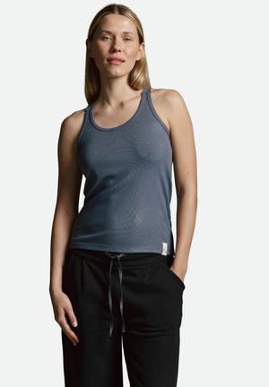 Blaues Rippentop mit dünnen Trägern, ausgestattet mit einem runden Halsausschnitt und einem kleinen Logostreifen am Saum, kombiniert mit schwarzen Sweatpants mit Kordelzug.