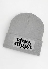 Gray knitted beanie with a cuffed design featuring a rectangular patch that reads "vino, digga" in bold black font.