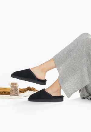 Pantofole in suede nero con un interno morbido, punta arrotondata e suola in gomma flessibile. Abbinato a un tessuto grigio chiaro.