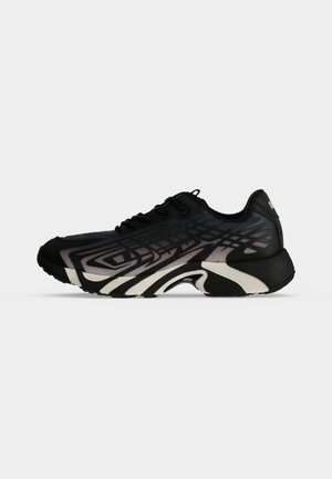 Zapatilla deportiva negra y gris con patrones geométricos en capas y suela gruesa y esculpida mostrada de lado sobre un fondo blanco.
