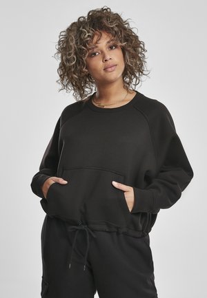 Svart hettegenser med rund hals, raglan-ermer og frontlomme. Har snor i bunnen og myk, strukturert stoff.