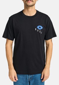 Camiseta negra de manga corta con un gráfico de ojo azul y letras blancas de RVCA en el lado izquierdo del pecho. Confeccionada en suave tela de algodón.