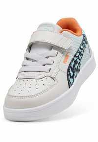 Baskets en cuir blanc avec accents gris, motif texturé noir et bleu sur le côté, doublure orange, bande velcro et boîte à orteils perforée.