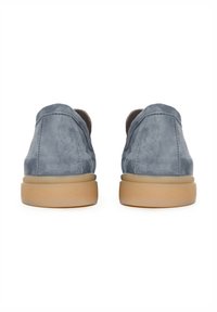 Paire de chaussures en daim bleu avec semelles en caoutchouc beige, vues de dos sur un fond blanc.