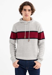 Sudadera de punto gris claro con una francha horizontal roja y negra en el pecho, con cordones y puños acanalados. Corte casual.