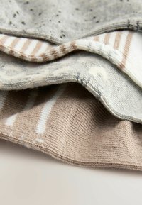 Set aus drei gestrickten Textilien in verschiedenen Beige- und Grautönen, mit gestreiften und gemusterten Designs sowie einer sanften Textur.