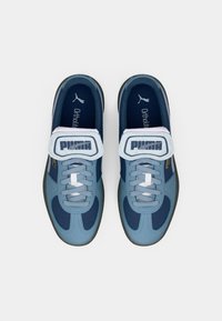 Puma tossud, millel on kerge sinise ja tumesinise sünteetilise materjali segu, paelakujundus ja silmapaistev Velcro rihm logoga.