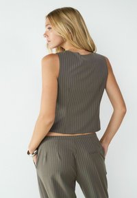 Bruin, gestreept cropped top met een ronde halslijn. Gemaakt van een soepele stof, heeft een getailleerde pasvorm en wordt gecombineerd met bijpassende broeken.