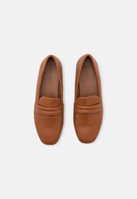 Paire de mocassins en cuir beige avec bouts carrés arrondis et détails de couture, vue de dessus sur un fond blanc uni.