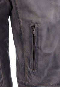 Donkergrijze leren jas met een ritszak op de linkerborst, een gladde textuur en zichtbare stikdetails.