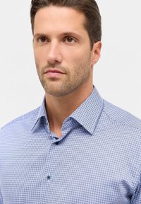 Blauw gestructureerd shirt met kleine geometrische vormen, knoopsluiting, en een gladde katoenen textuur. Subtiele contrasterende knopen.