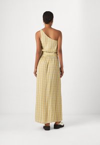 Eén-schouder maxi-jurk in geel en wit ruitpatroon, met een ceintuur in de taille en een losse pasvorm. Gladde stof, enkellange ontwerp.
